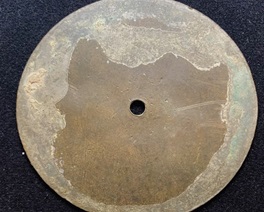 A brass artifact of circular shape with a small central hole